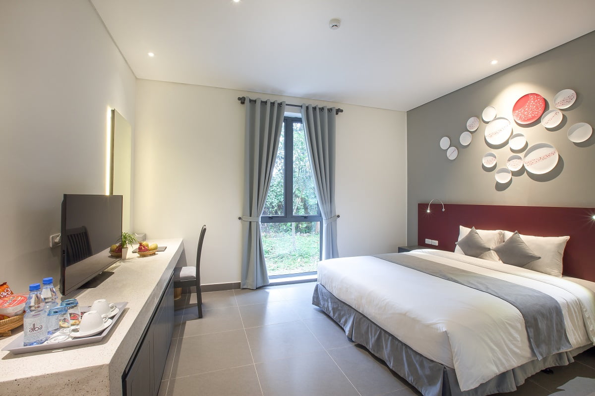Compact standard Alba Inn room with bed and garden-facing window at Alba Wellness Valley Hue